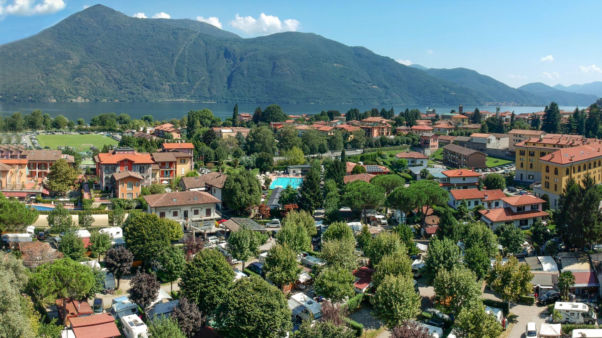 Vista panoramica di un villaggio con lago e montagne sullo sfondo.