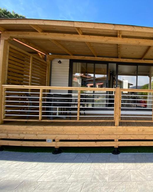 Terrazza in legno con copertura, sedie e ampie porte vetrate.