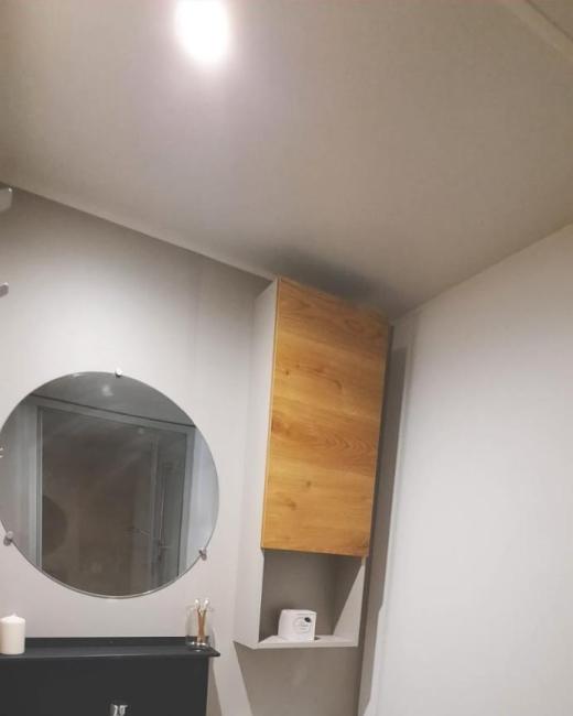 Bagno moderno con lavabo rotondo, specchio, WC e mobili in legno.