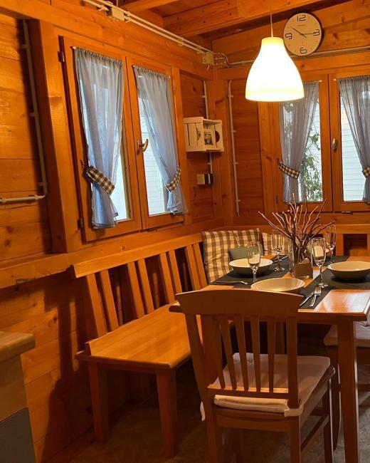 Accogliente sala da pranzo in legno con tavolo apparecchiato e finestra aperta.