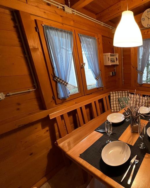 Accogliente sala da pranzo in legno con tavola apparecchiata e luce calda.