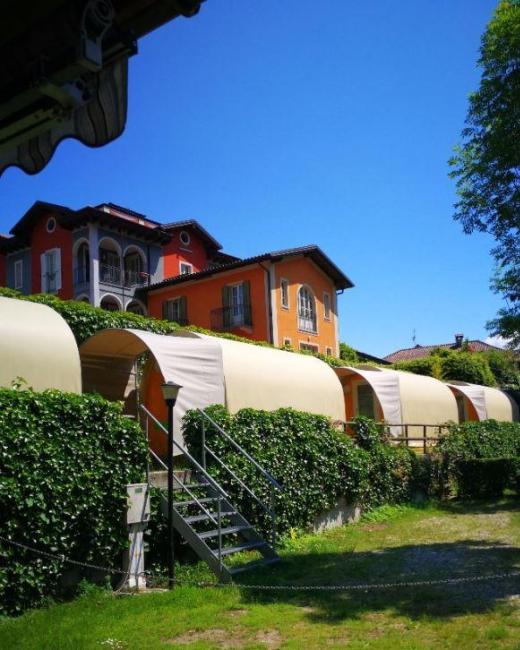 Case colorate con tettoie e giardino verde sotto un cielo azzurro.