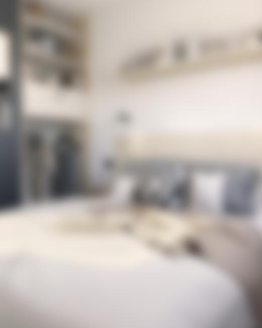 Camera da letto moderna con letto, cuscini e mensole decorative.