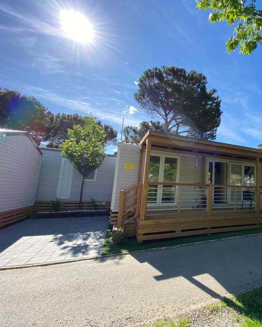 Case mobili immerse nel verde, con veranda in legno e cielo sereno.