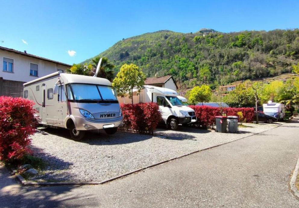 Camper parcheggiati in un'area verde con vista sulle colline.